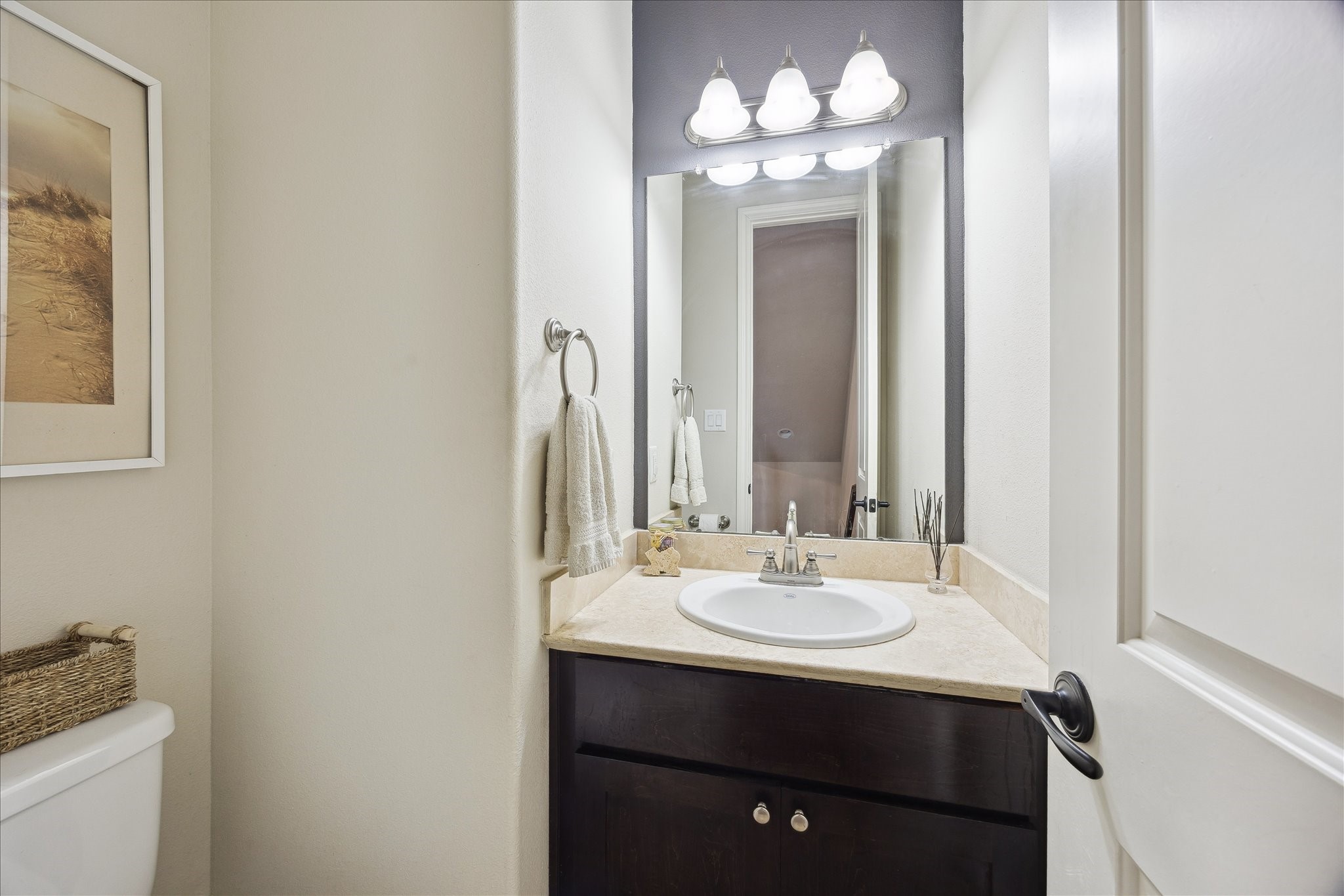1110 West 25th Street Houston, TX 77008 - Photo 13 of 40 This stylish powder room offers a perfect blend of function and sophistication, ideal for guests. Featuring a sleek vanity with a stone countertop, modern fixtures, and warm, soft lighting, the space feels polished and inviting. Neutral tones and thoughtful details create a clean, timeless look that complements the rest of the home