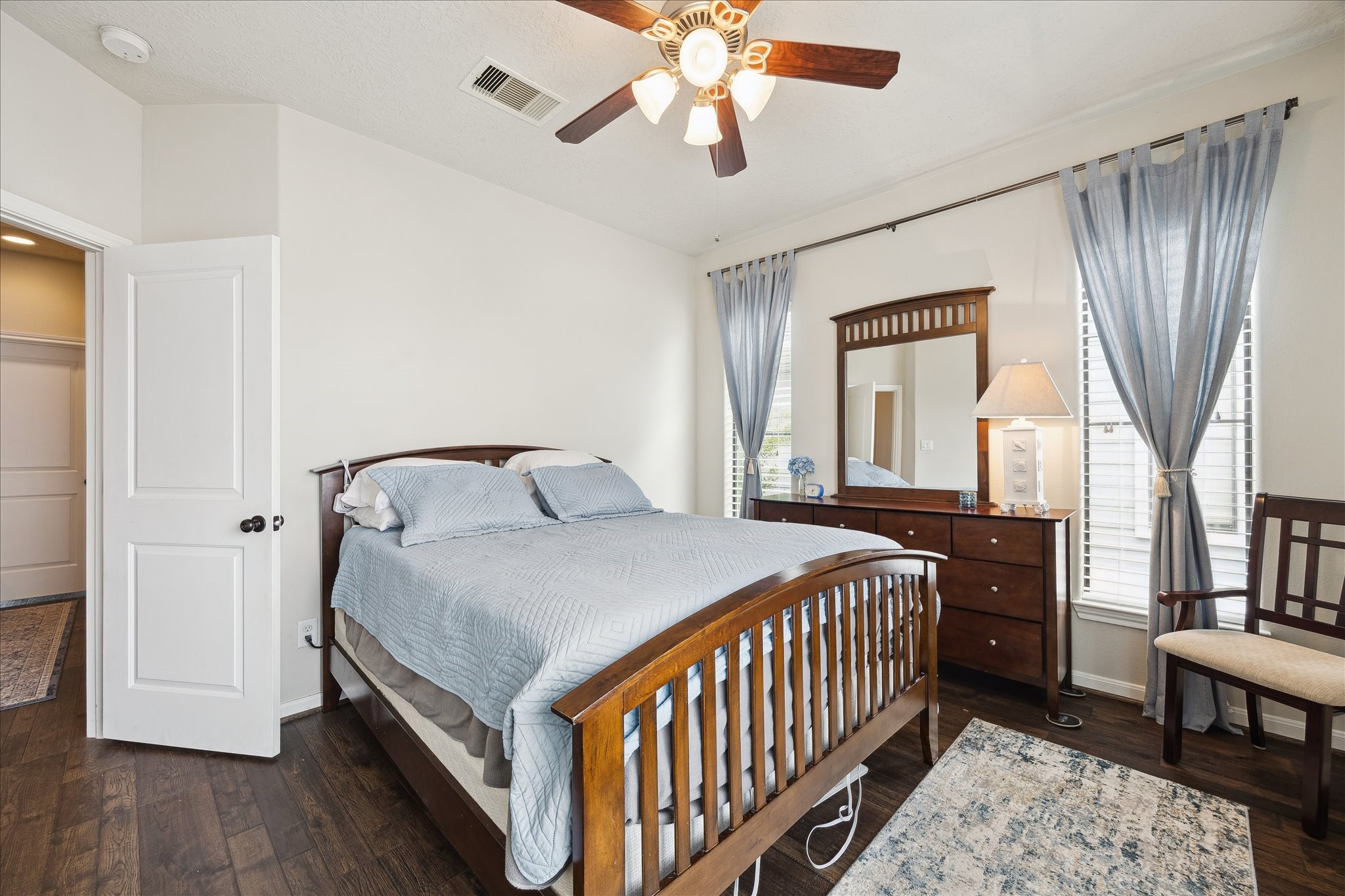 1110 West 25th Street Houston, TX 77008 - Photo 14 of 40 This bright and inviting secondary bedroom offers a comfortable retreat with a timeless, tranquil feel. Warm hardwood floors, soft neutral walls, and abundant natural light create a serene atmosphere, while the ceiling fan adds year-round comfort. The space easily accommodates a full bedroom suite and includes generous closet space, making it ideal for guests, a home office, or a cozy personal sanctuary.