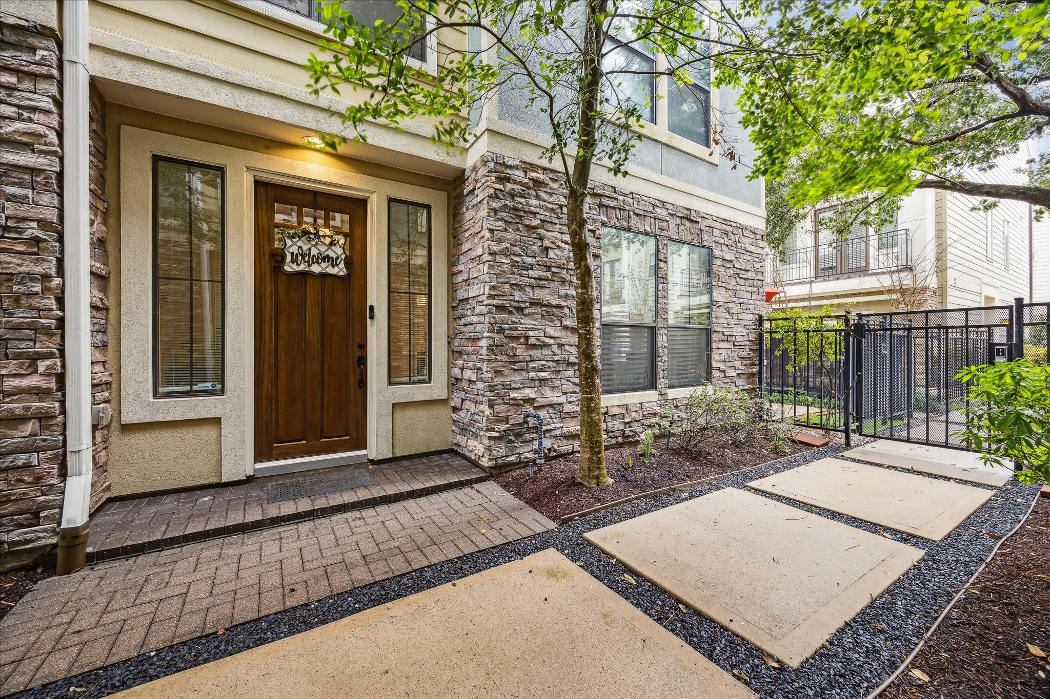 1110 West 25th Street Houston, TX 77008 - Photo 2 of 40 A rich wood front door, framed by tall sidelights, creates a warm and welcoming focal point, while the elegant stone façade adds timeless character and upscale appeal.