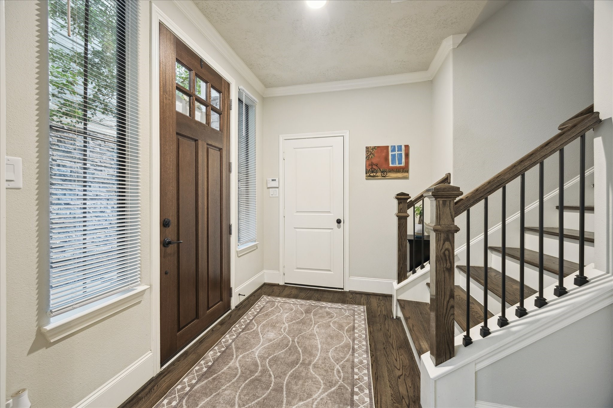 1110 West 25th Street Houston, TX 77008 - Photo 3 of 40 Rich hardwood floors lead you into the home, complemented by crisp crown molding and soft, neutral tones that make the space feel fresh and timeless. The staircase, with its wood handrail and modern iron balusters, adds a touch of architectural interest and sets the stage for the quality craftsmanship found throughout.