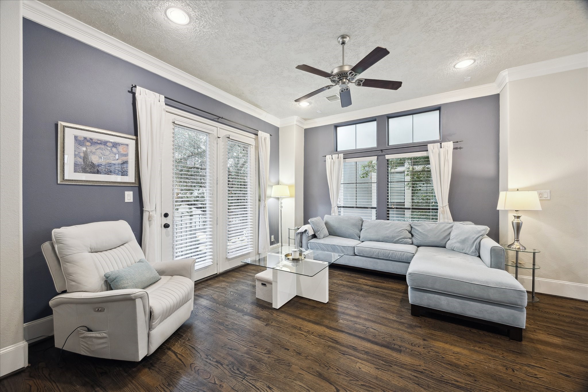 1110 West 25th Street Houston, TX 77008 - Photo 6 of 40 This beautifully appointed living room is designed to impress while still feeling warm and inviting. Rich hardwood floors, crown molding, and recessed lighting create a polished backdrop, while the open layout offers generous space for both relaxing and entertaining. Oversized windows and French doors fill the room with natural light and provide an effortless flow to the outdoor balcony.