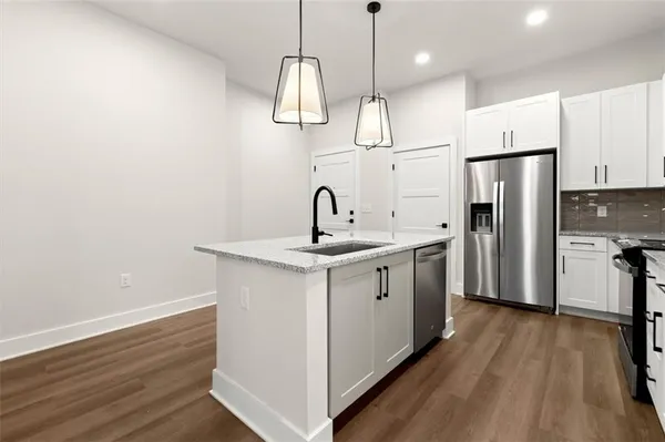 a kitchen with stainless steel appliances granite countertop a sink a stove a refrigerator and island with wooden floor