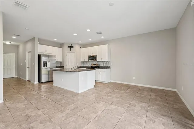 a large kitchen with stainless steel appliances kitchen island granite countertop a stove top oven a sink and a refrigerator