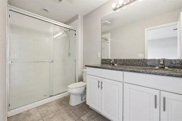 a bathroom with a granite countertop sink toilet and shower