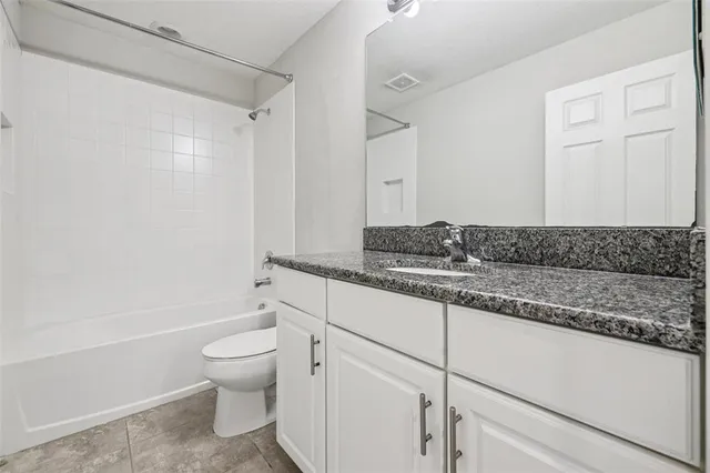 a bathroom with a granite countertop sink a toilet and shower