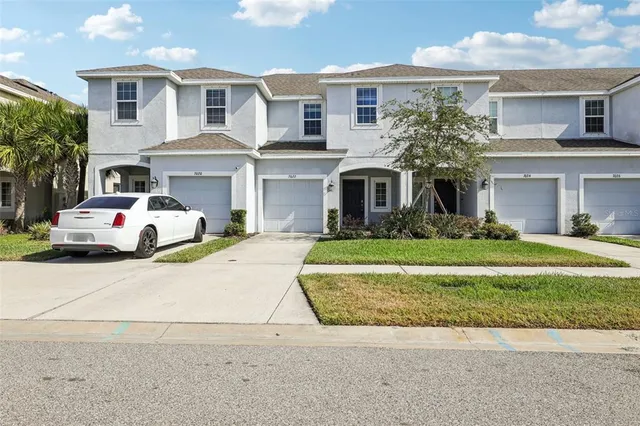 a front view of a house with a garden and palm trees