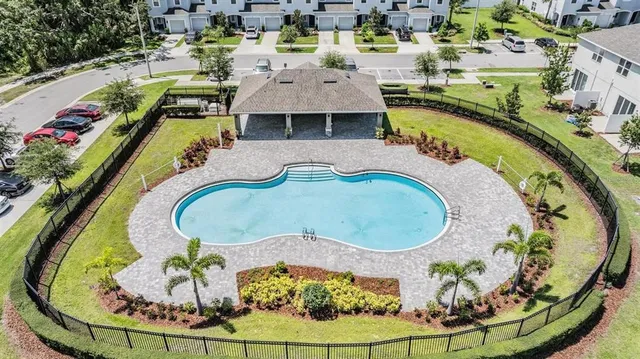 an aerial view of a swimming pool with outdoor seating and yard