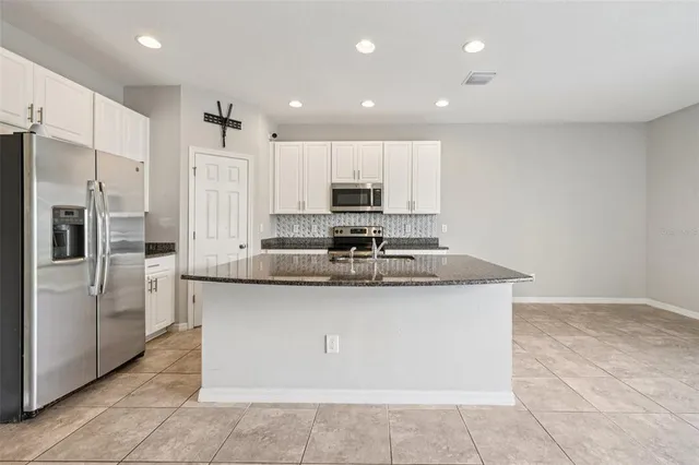 a kitchen with stainless steel appliances granite countertop a sink a stove a refrigerator and a microwave