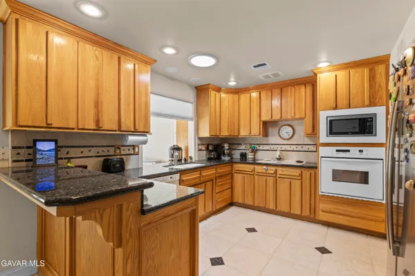 a kitchen with stainless steel appliances granite countertop a stove a sink dishwasher and a microwave oven with cabinets