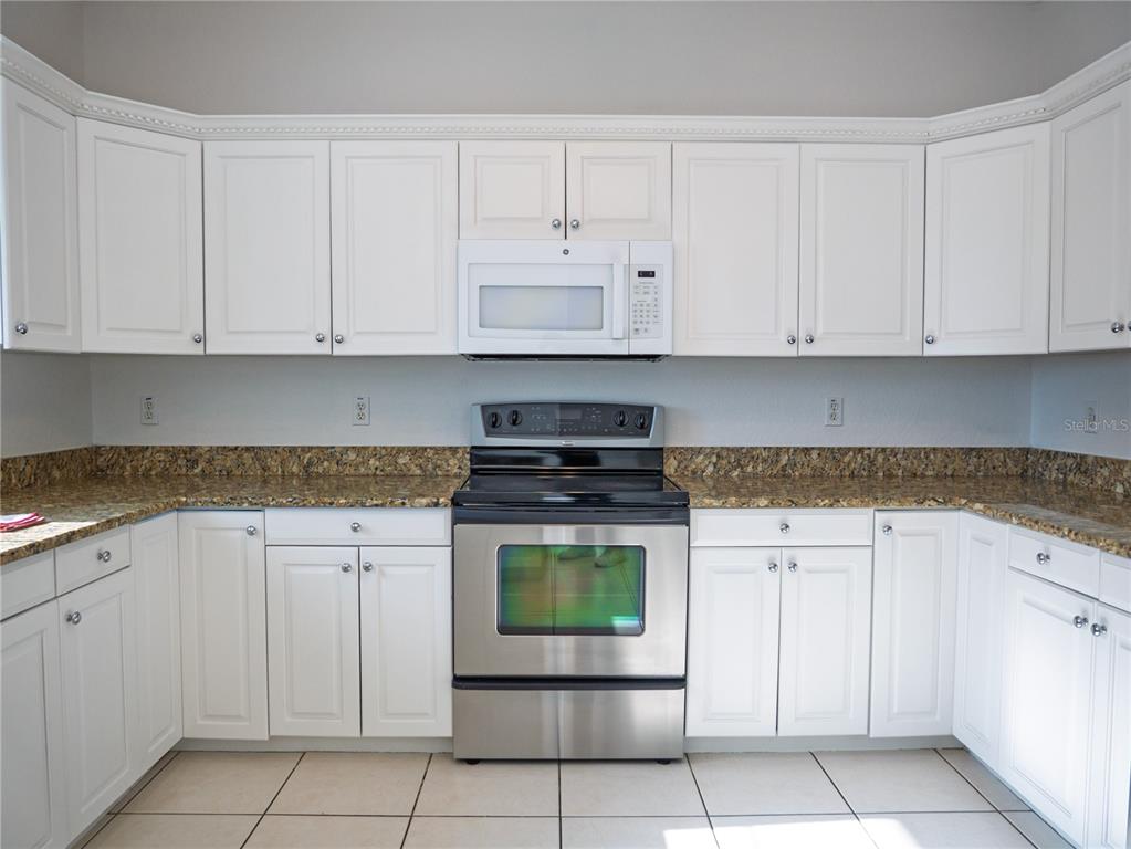15473 Gulf Boulevard Madeira Beach, FL 33708 - Photo 13 of 40 a kitchen with granite countertop white cabinets and stainless steel appliances