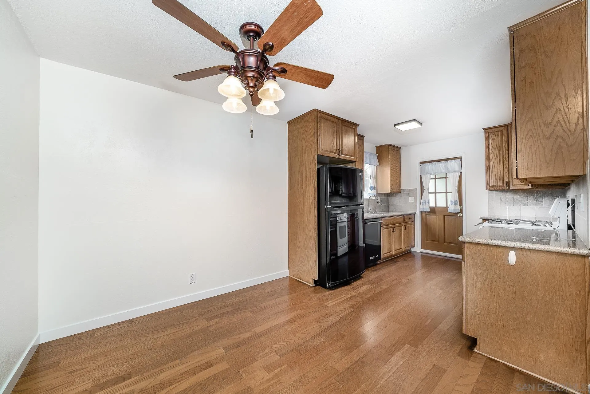 4047 Thomas Street Oceanside, CA 92056 - Photo 7 of 21 a kitchen with stainless steel appliances granite countertop a refrigerator a stove a sink and white cabinets with wooden floor