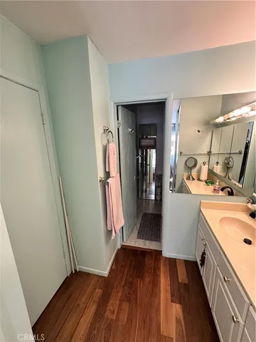 a walk in closet with wooden floor and cabinets