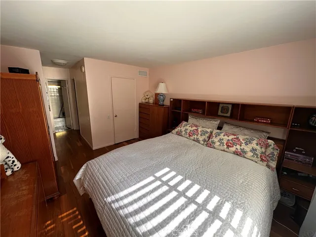 a bed sitting in a bedroom and dressers next to a window