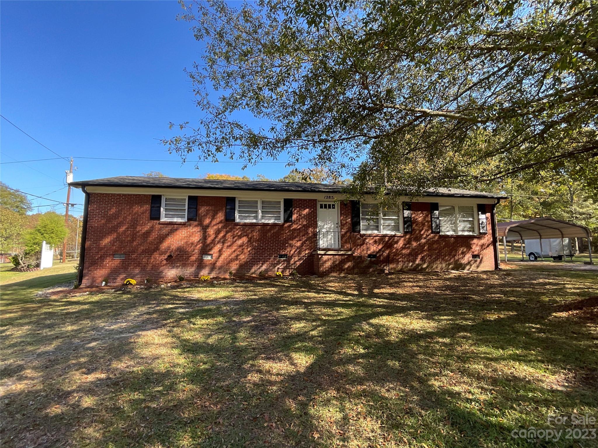 a view of a house with a small yard and a large tree