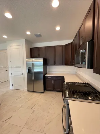 a large kitchen with kitchen island a sink stainless steel appliances and a large window