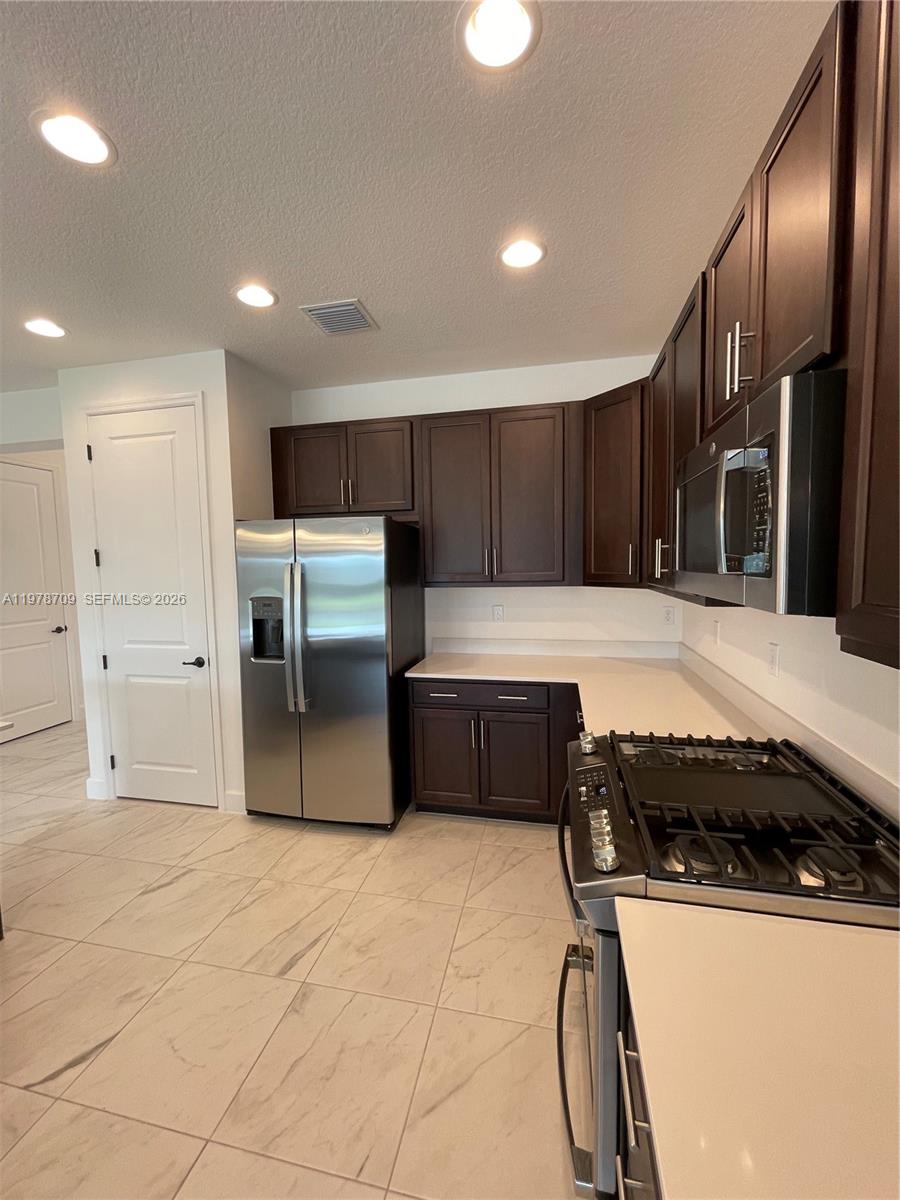 10922 Southwest Meandering Mile Road, Unit 10922 Port St. Lucie, FL 34987 - Photo 11 of 56 a kitchen with granite countertop a refrigerator and a stove top oven