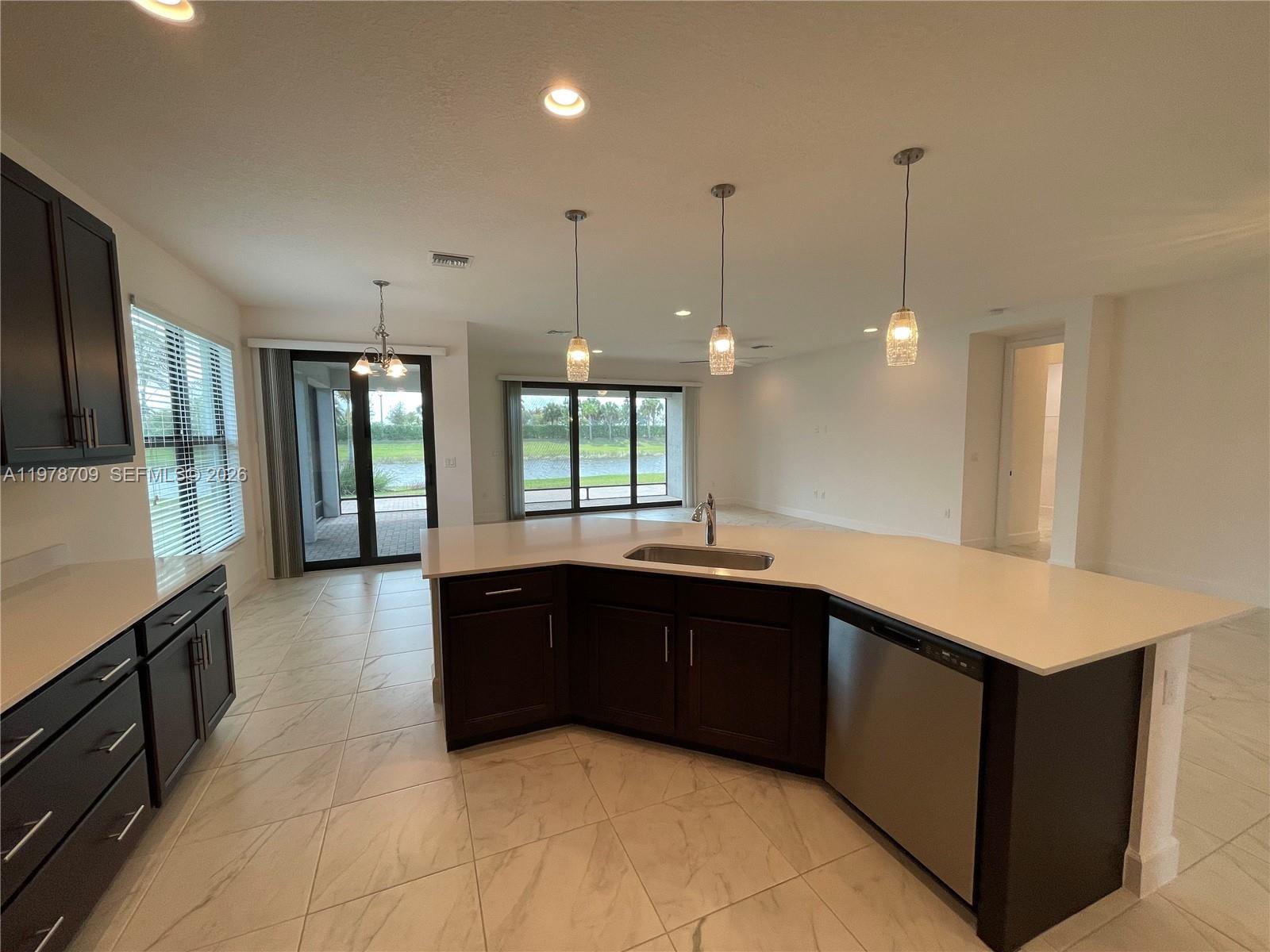 10922 Southwest Meandering Mile Road, Unit 10922 Port St. Lucie, FL 34987 - Photo 12 of 56 a large kitchen with kitchen island a sink stainless steel appliances and a large window