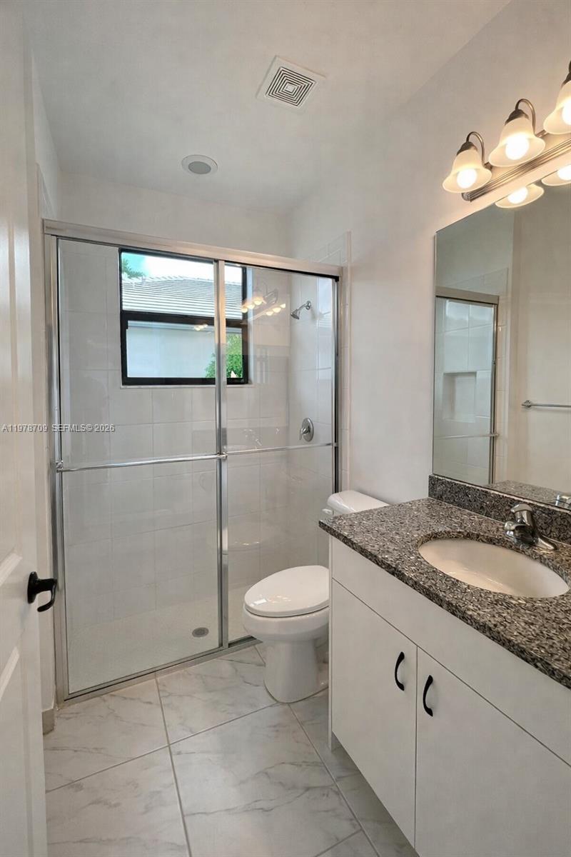 10922 Southwest Meandering Mile Road, Unit 10922 Port St. Lucie, FL 34987 - Photo 22 of 56 a bathroom with a granite countertop sink toilet and shower