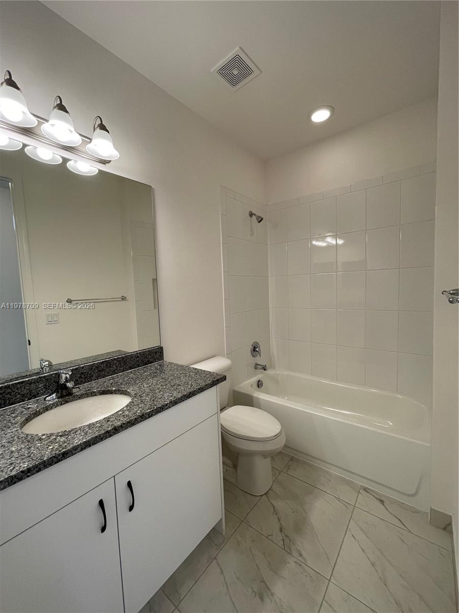 10922 Southwest Meandering Mile Road, Unit 10922 Port St. Lucie, FL 34987 - Photo 26 of 56 a bathroom with a granite countertop sink a toilet and bathtub