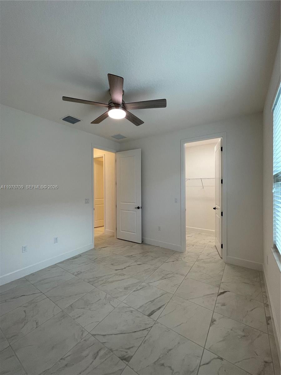 10922 Southwest Meandering Mile Road, Unit 10922 Port St. Lucie, FL 34987 - Photo 27 of 56 an empty room with a chandelier fan and windows