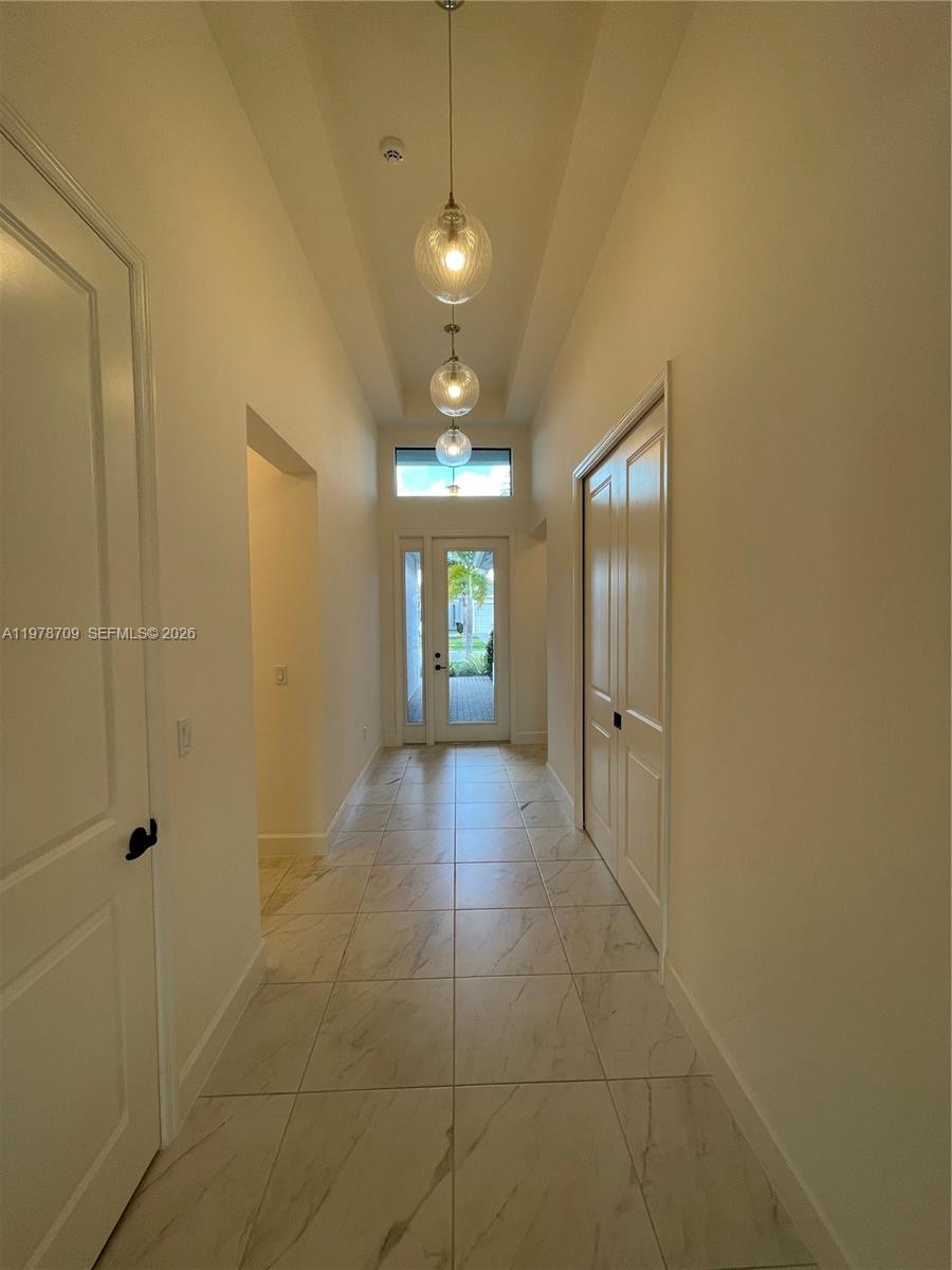 10922 Southwest Meandering Mile Road, Unit 10922 Port St. Lucie, FL 34987 - Photo 3 of 56 a view of a hallway with chandelier and a bathroom