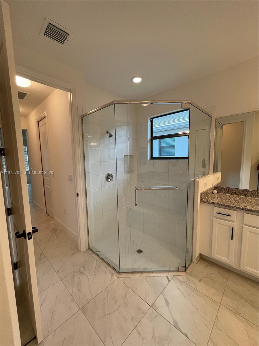 10922 Southwest Meandering Mile Road, Unit 10922 Port St. Lucie, FL 34987 - Photo 37 of 56 a bathroom with a granite countertop sink a mirror and a shower
