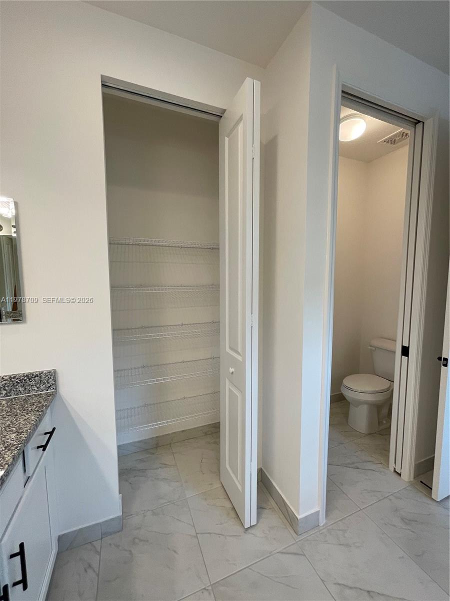 10922 Southwest Meandering Mile Road, Unit 10922 Port St. Lucie, FL 34987 - Photo 38 of 56 a bathroom with a toilet and a sink