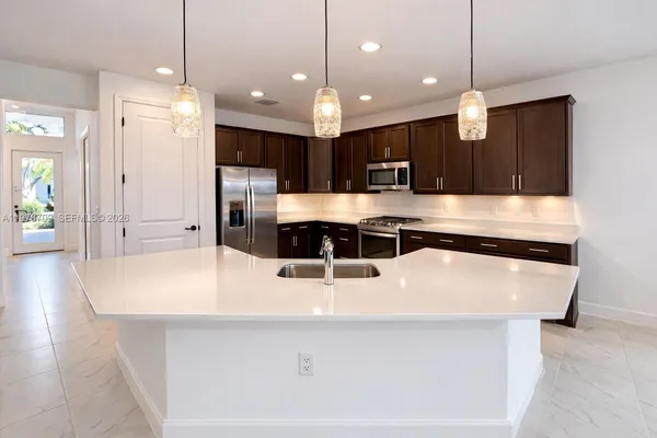 a large kitchen with kitchen island a sink a counter top and stainless steel appliances