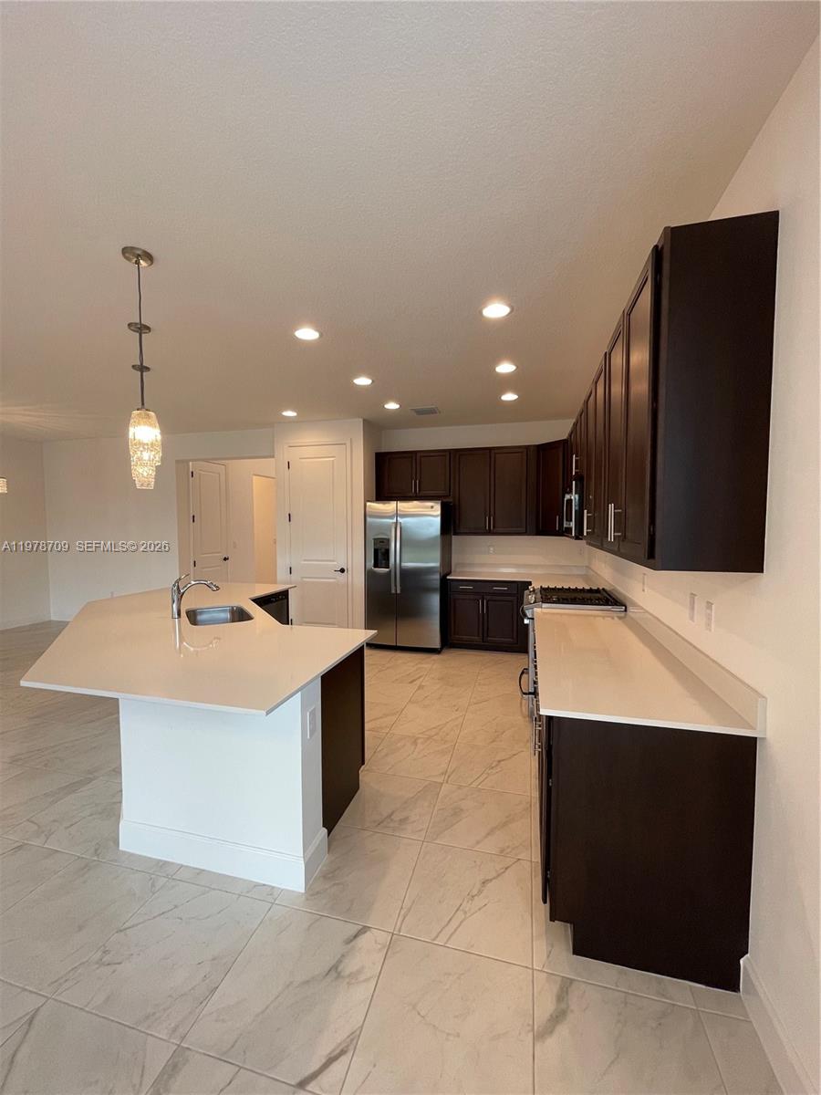 10922 Southwest Meandering Mile Road, Unit 10922 Port St. Lucie, FL 34987 - Photo 9 of 56 a large kitchen with kitchen island a sink a counter top and stainless steel appliances