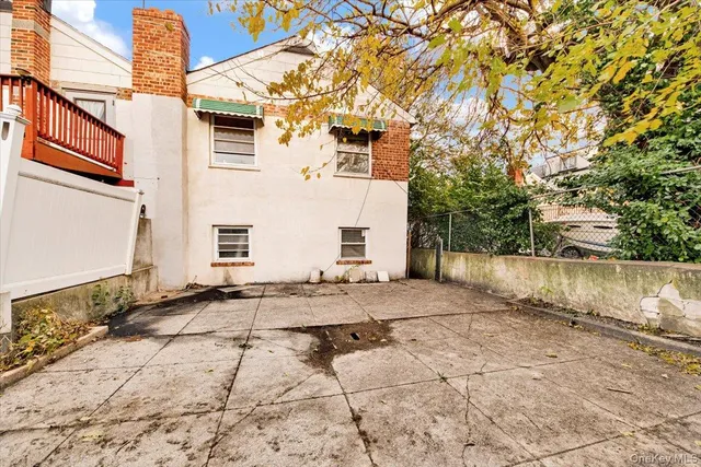 a view of a white house with a large tree in front of it