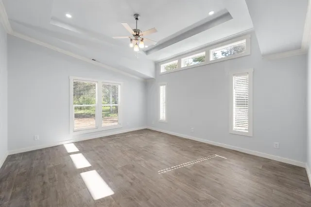 an empty room with wooden floor chandelier and windows