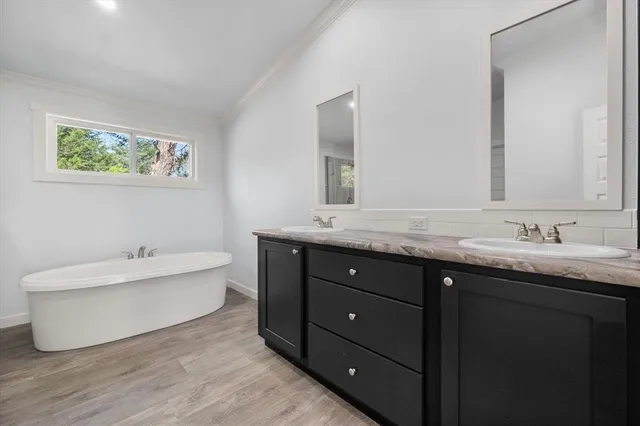 a bathroom with a tub double sink and mirror