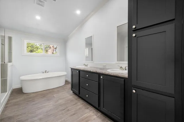 a bathroom with a double vanity sink mirror and bathtub