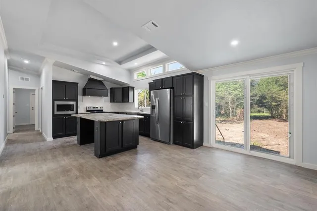a kitchen with stainless steel appliances kitchen island granite countertop a refrigerator and a sink
