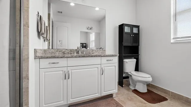 a bathroom with a granite countertop toilet and a sink