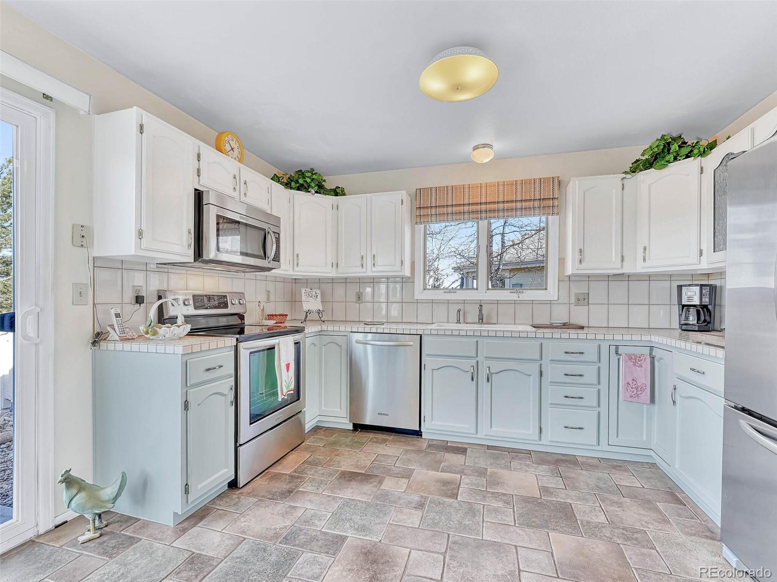 9 Stonehaven Court Highlands Ranch, CO 80130 - Photo 7 of 40 a kitchen with white cabinets appliances a sink and a window