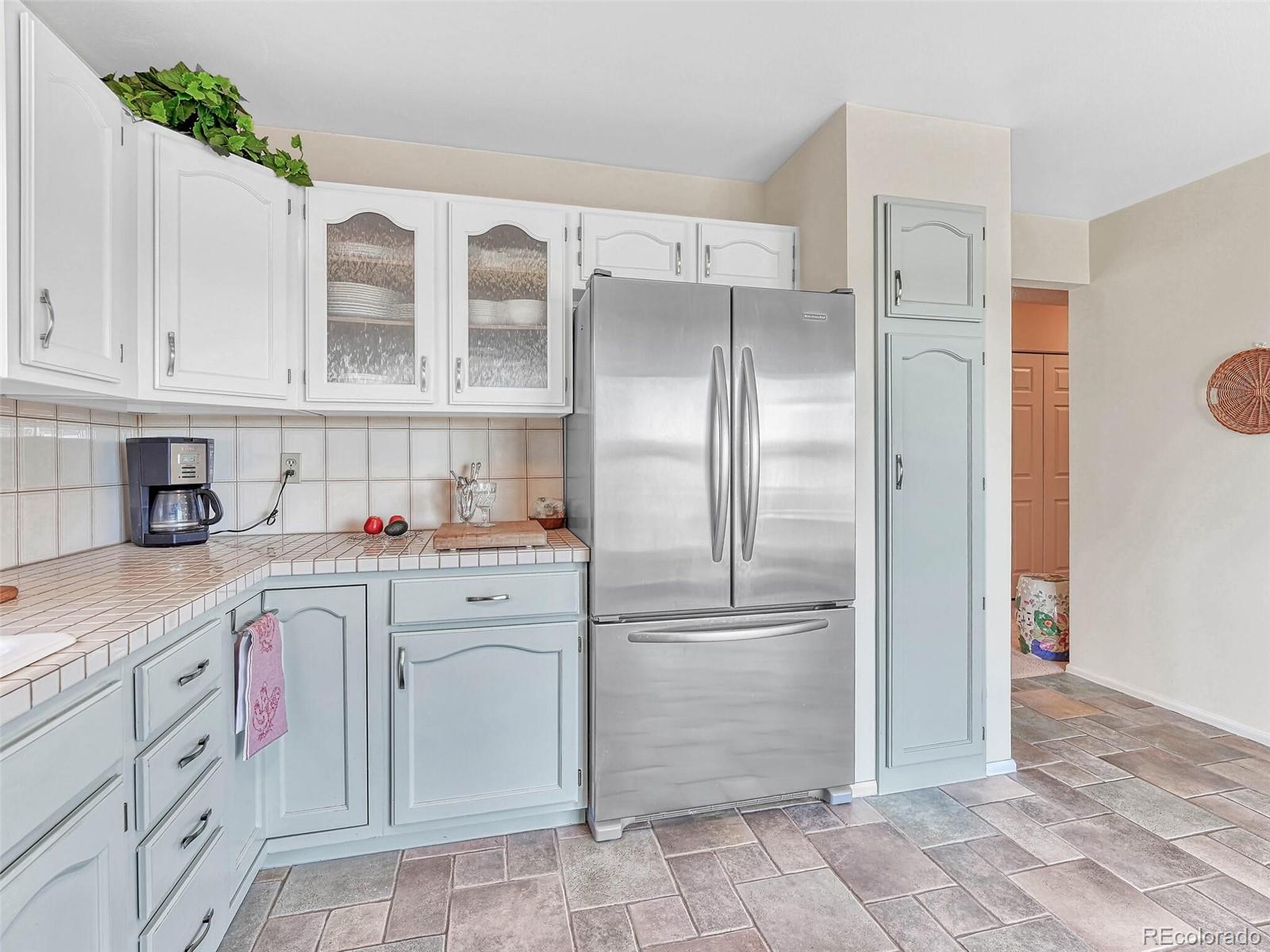 9 Stonehaven Court Highlands Ranch, CO 80130 - Photo 10 of 40 a kitchen with white cabinets and refrigerator