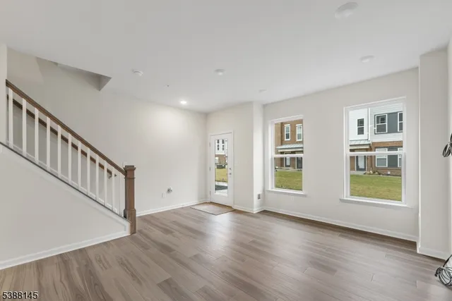 a view of an empty room with wooden floor and windows