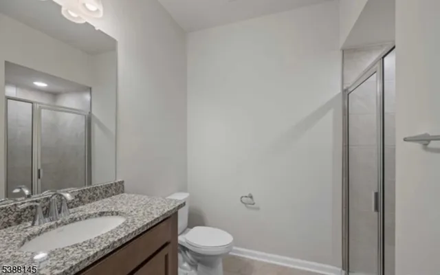 a bathroom with a granite countertop sink a mirror and a toilet
