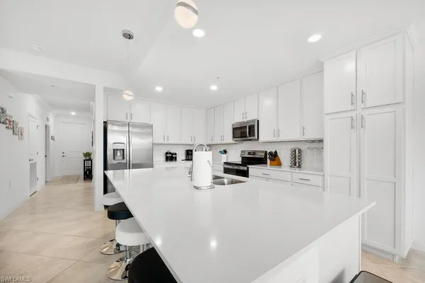 a large white kitchen with lots of counter space refrigerator and white cabinets