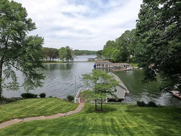 a view of a lake with a yard and large trees