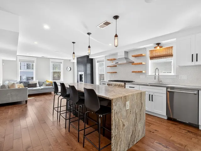 a kitchen with stainless steel appliances granite countertop a table chairs stove and wooden floor