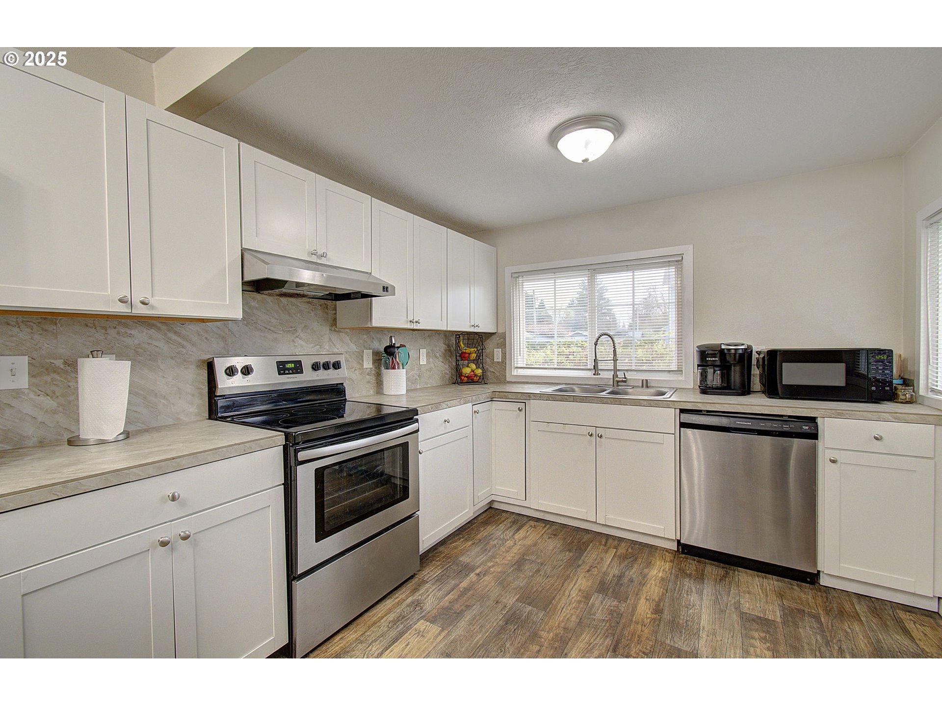 511 4th Avenue Southwest Castle Rock, WA 98611 - Photo 11 of 37 a kitchen with stainless steel appliances granite countertop a sink dishwasher a stove and white cabinets with wooden floor