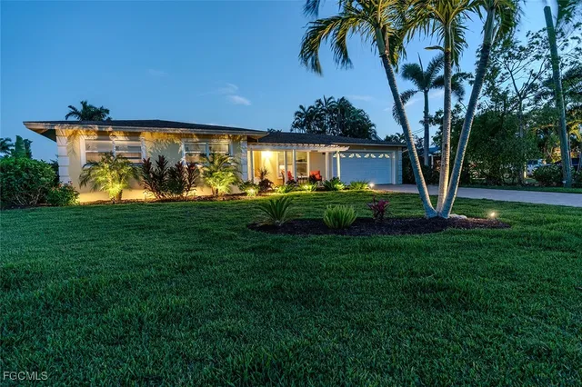 a view of a house with a big yard and palm trees