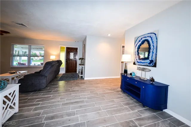 a living room with couches dresser and a large window with wooden floor