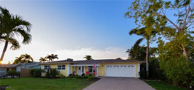 a view of a white house with a yard and potted plants