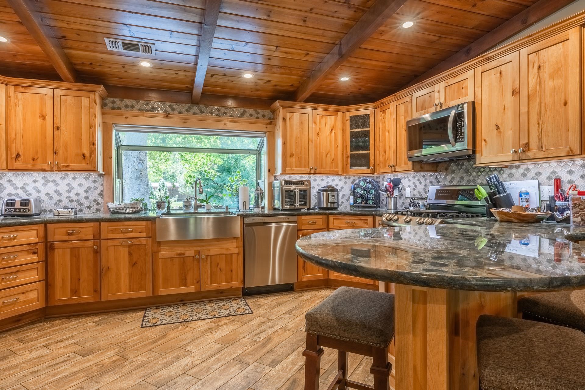 325 Mt Tom Road Bishop, CA 93514 - Photo 11 of 33 a kitchen with stainless steel appliances granite countertop wooden cabinets a sink and a large window