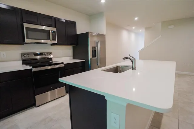 a kitchen with a sink a microwave a refrigerator and cabinets