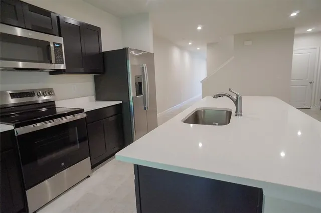 a kitchen with stainless steel appliances a sink microwave and refrigerator