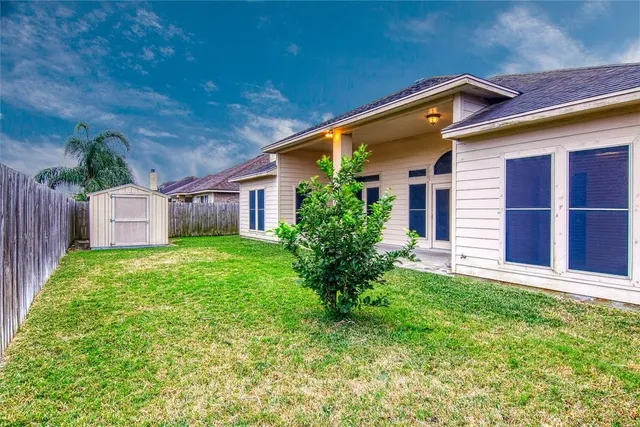 a backyard of a house with plants and large tree